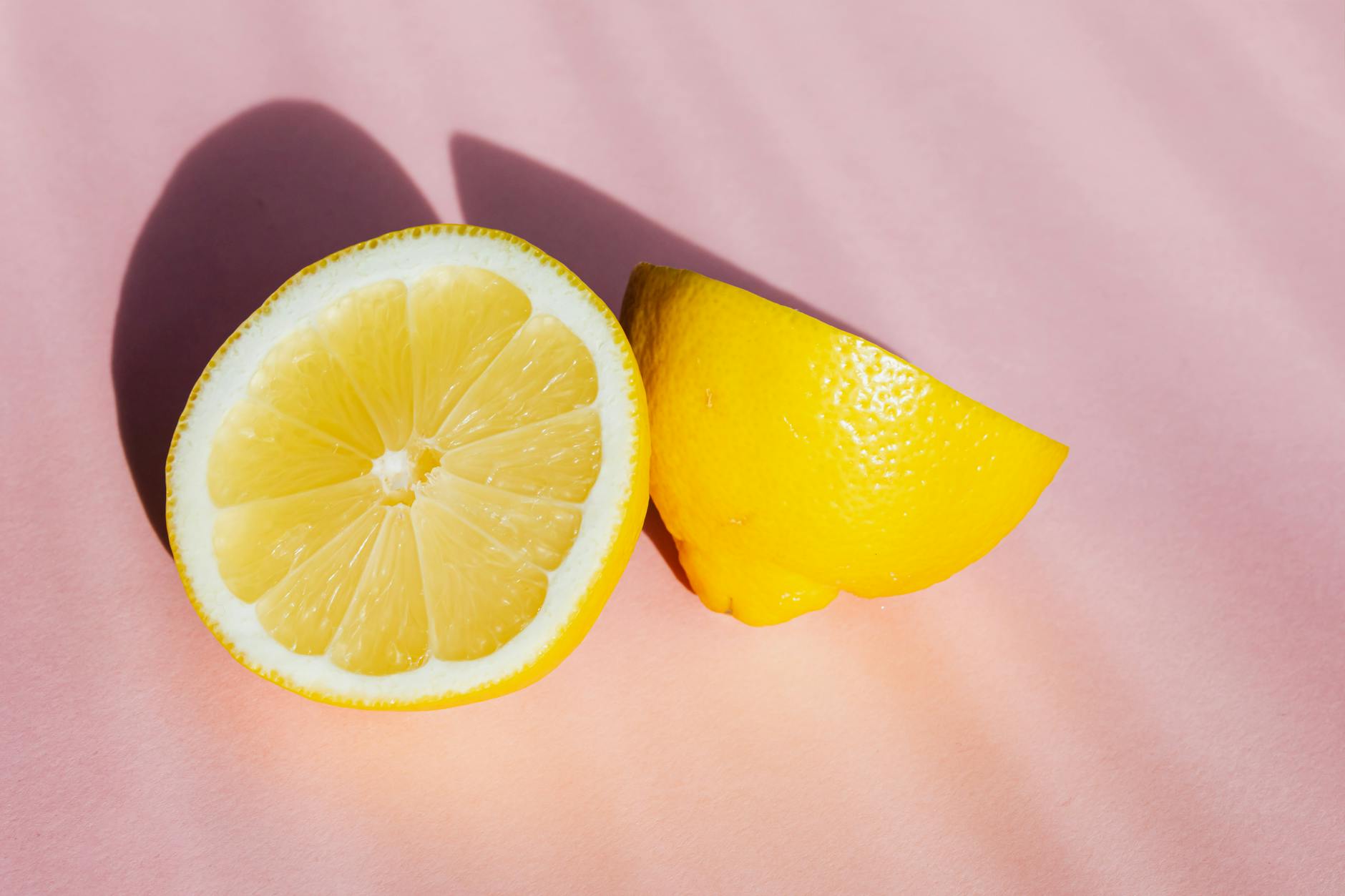 Fresh lemon halves on a pink background in bright sunlight, symbolizing renewal and sensation