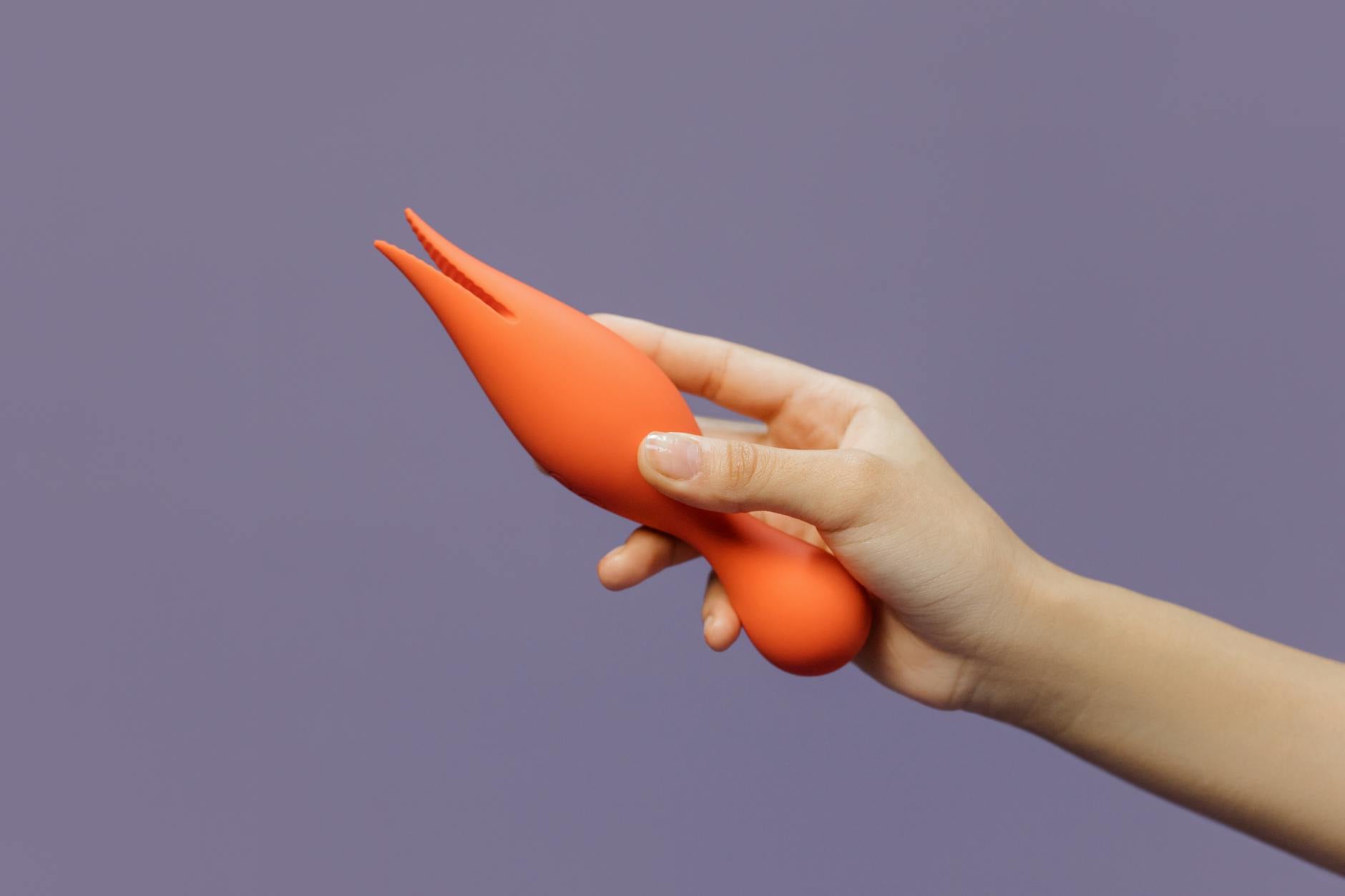 Close-up of a hand holding a vibrator against a minimalistic backdrop, representing self-care and sensual exploration.