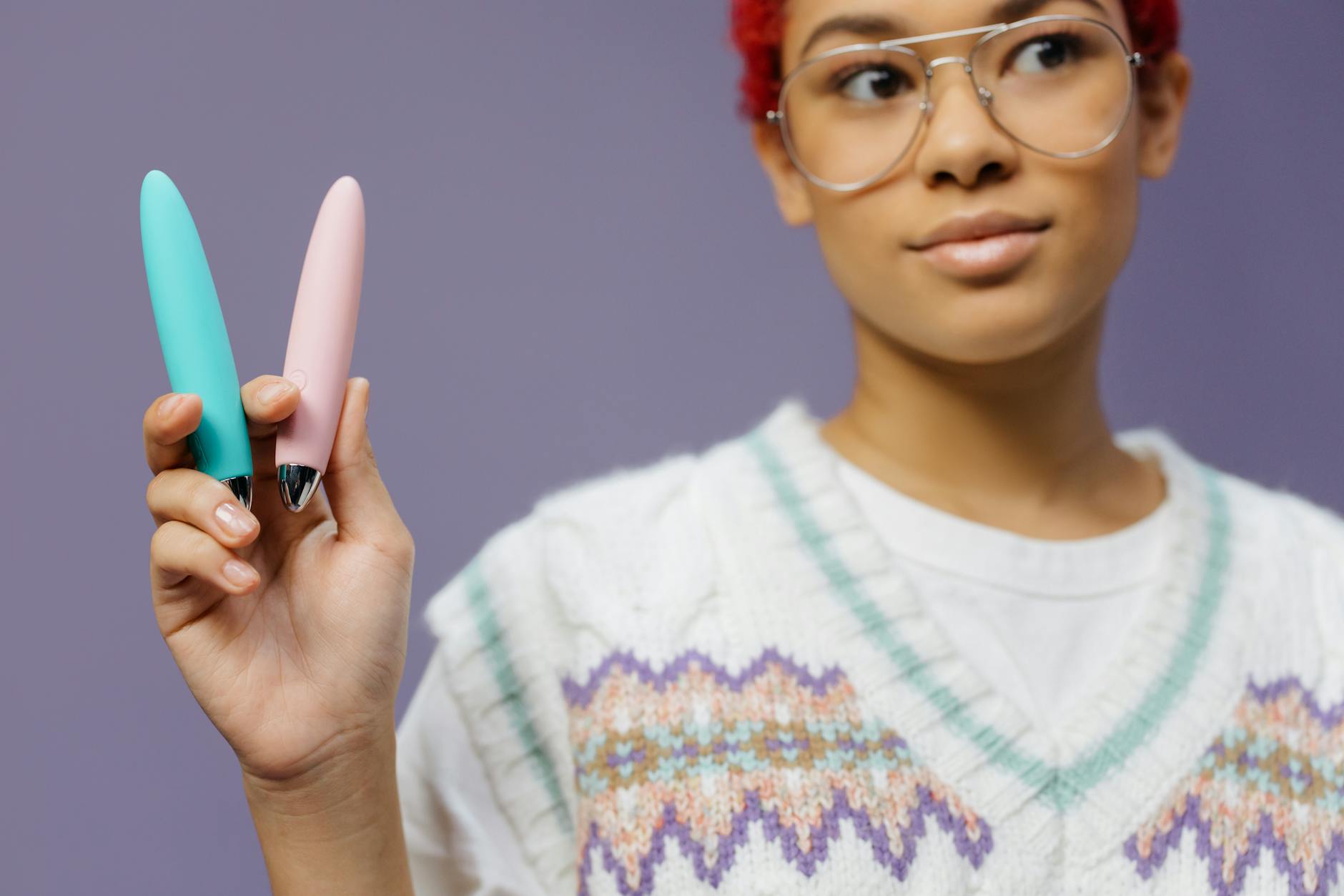 A woman holding colorful vibrators, representing tools for rebuilding clitoral sensation