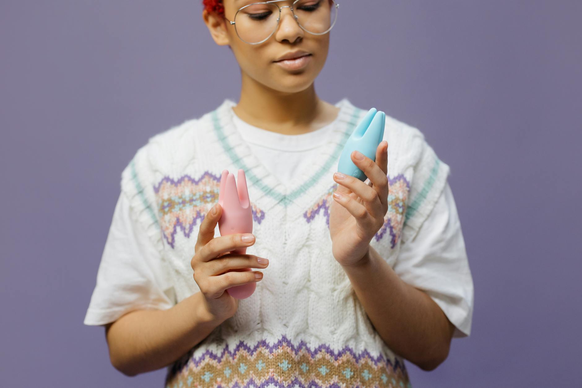 Person thoughtfully holding a blue silicone vibrator, representing reconnection with pleasure during life transitions.