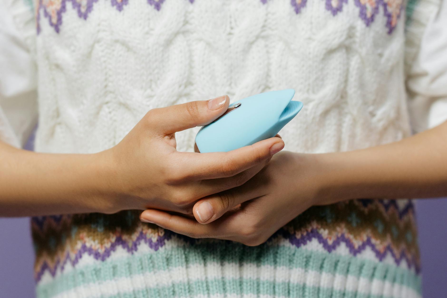 Close-up of hands holding a blue personal massager, representing discreet intimate wellness.